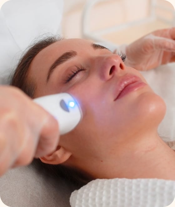 Woman receiving an LED laser device facial treatment