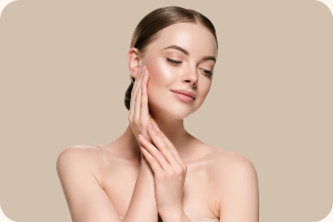 Woman touching her face against a beige backdrop